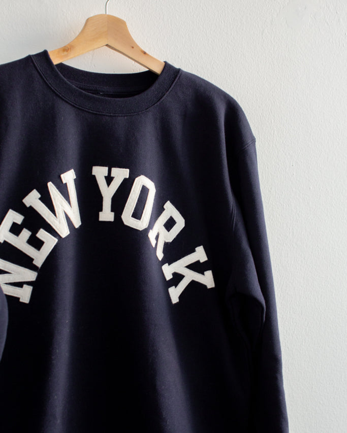Black sweatshirt with 'New York' text on a hanger against a white background