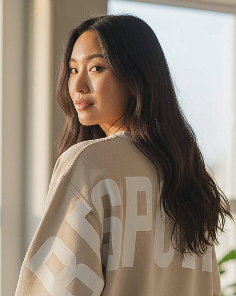 Woman wearing a beige sweatshirt with text in a modern indoor setting